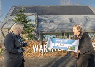Burgemeester Marjan van Kampen overhandigt het geldbedrag aan de vertegenwoordiger van de hospice in Schagen.