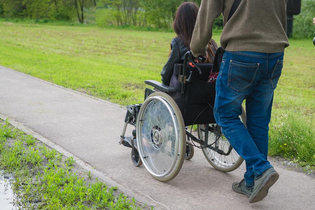 Persoon in rolstoel die voortgeduwd wordt.